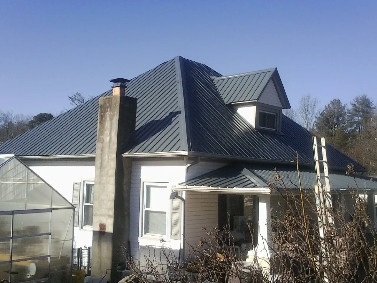 Dark blue standing seam metal roof on a white farmhouse with dormer — Slate & Tile Roof Repair by Roofing Brothers in Port Carbon