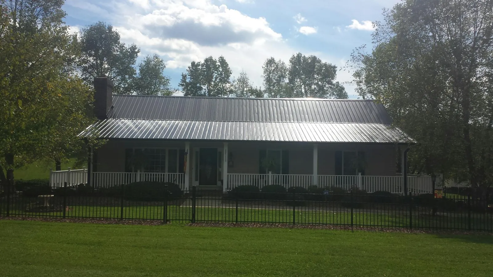 Gray metal roof on a brick ranch with a full width front porch — Gutter Guard Installation work by our crew in Port Carbon