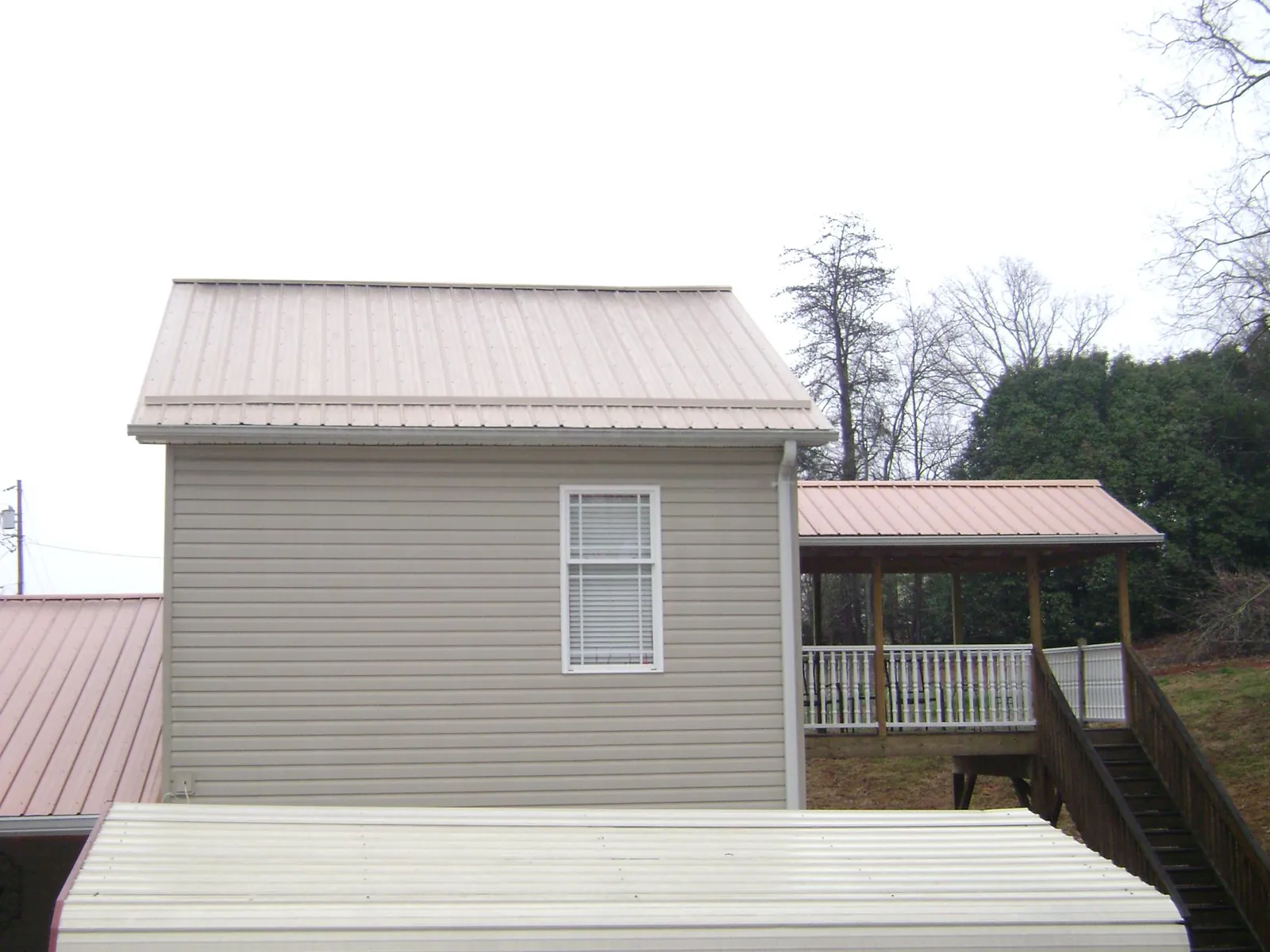 Tan metal roofs on a two story addition and attached porch, from a Roof Replacement job in Port Carbon