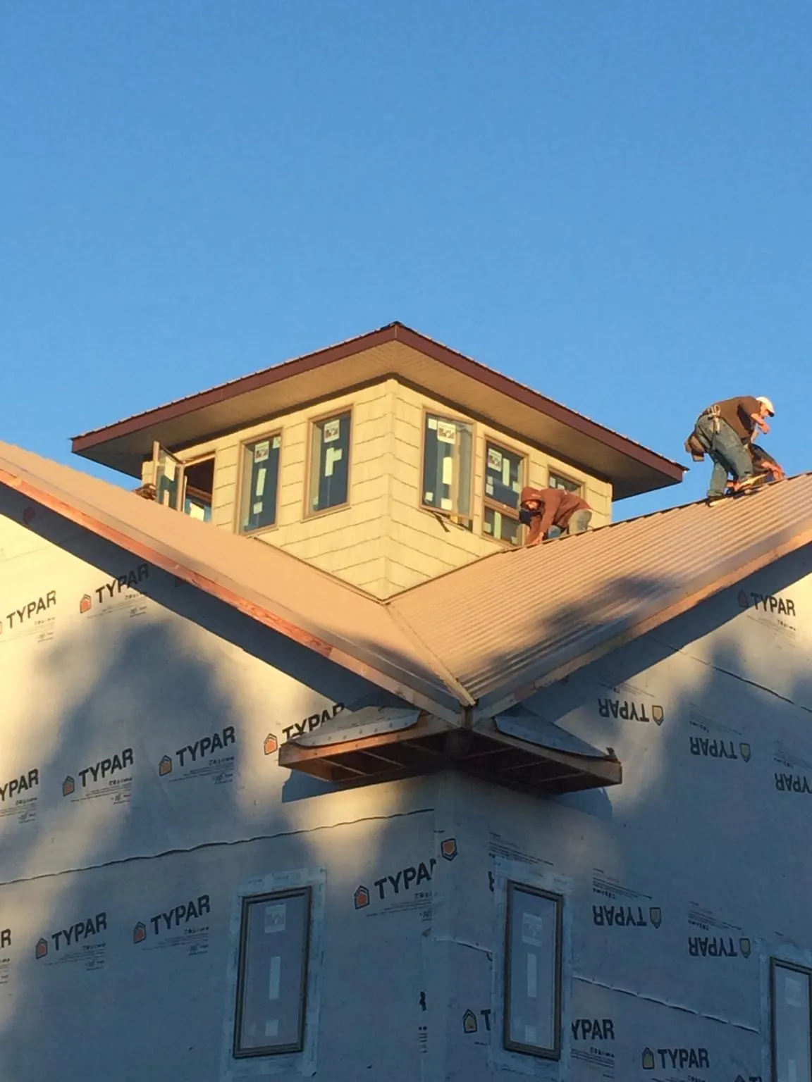 Roofers working around a rooftop cupola on a new metal roof at sunset — Roof Waterproofing in Port Carbon by Roofing Brothers